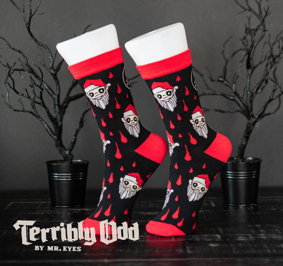 Side profile of black and red Creepmas crew socks by Spooky Cat Press featuring a repeating pattern of Little Orli, the Terribly Odd vampire elf character.