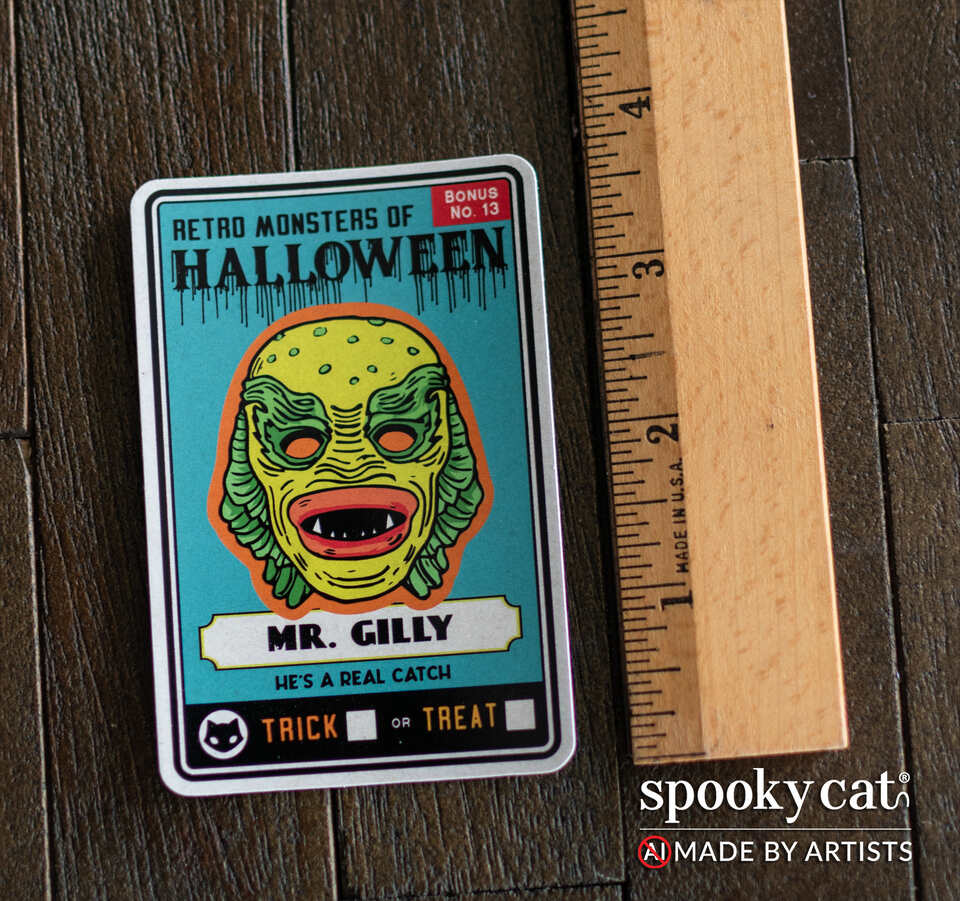 A retro-style Halloween collectible sticker featuring Mr. Gilly from the 'Retro Monsters of Halloween' series, displayed on a dark wood surface next to a wooden ruler for scale.