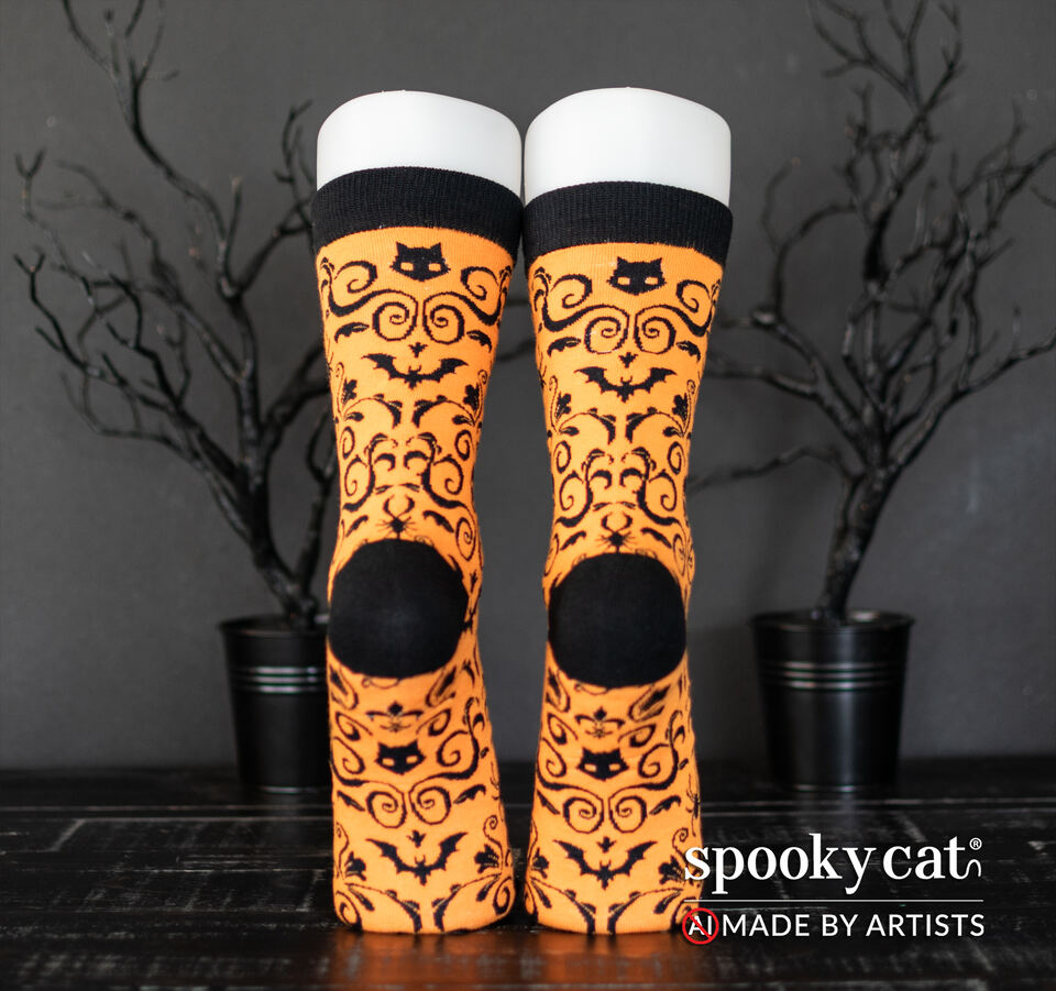 Orange socks with black gothic cats, bats, and skulls, Spooky Cat Press's signature Gothic Damask pattern worn on a foot mannequin.