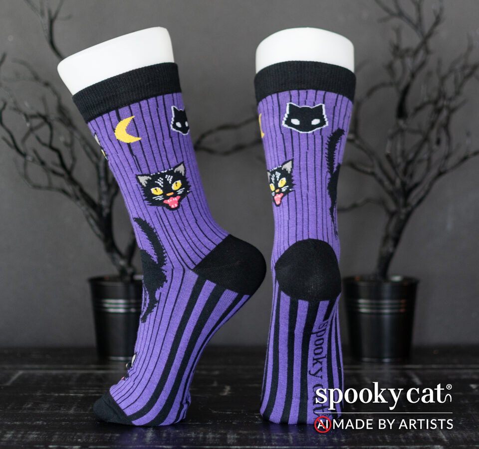 Vintage inspired purple Halloween socks with black cats, moons, and black stripes worn on a foot mannequin.