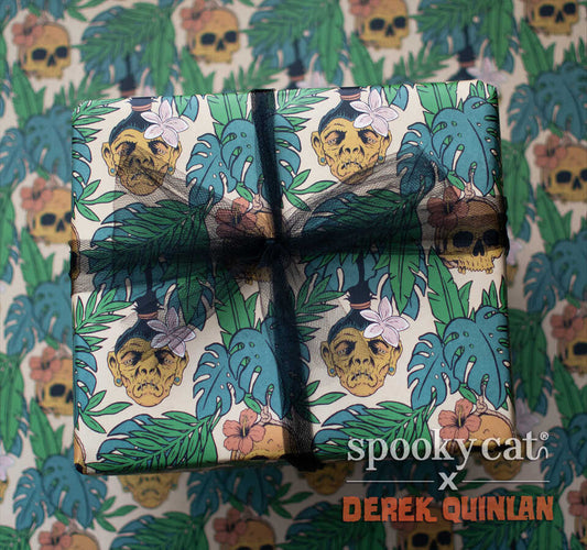 Wrapped gift box featuring Spooky Cat Press x Derek Quinlan tropical horror gift wrap with shrunken heads, monstera leaves, hibiscus flowers, and tiki-inspired spooky artwork on a cream background.