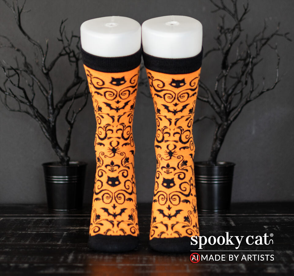 Orange socks with black gothic cats, bats, and skulls, Spooky Cat Press's signature Gothic Damask pattern worn on a foot mannequin.