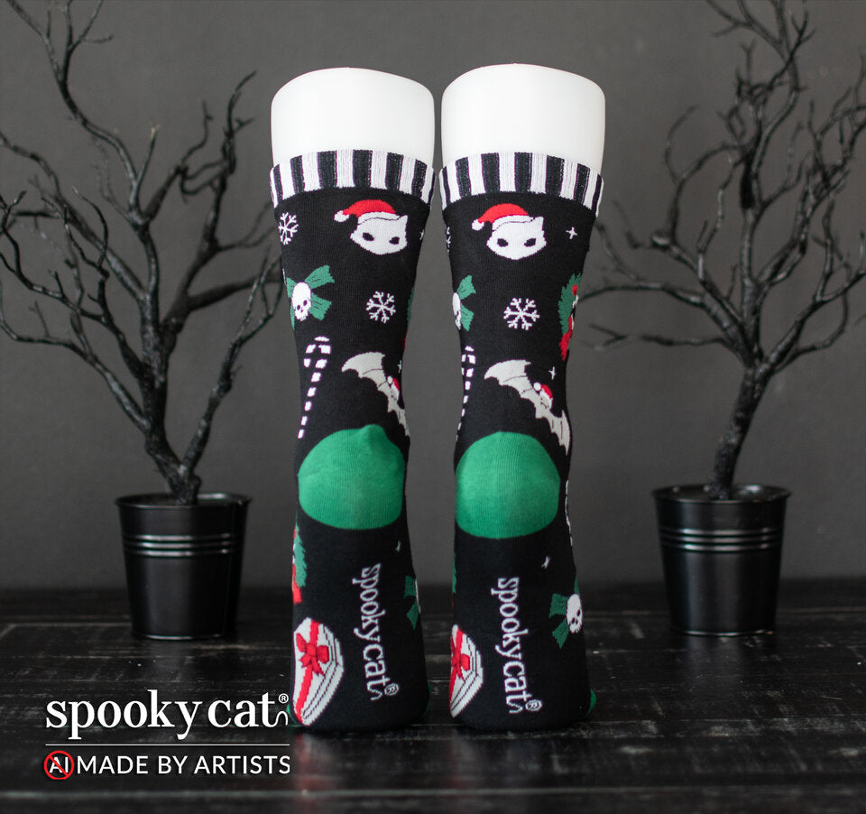 Back view of Spooky Cat Press Creepmas crew socks displayed on forms, showing green heel accents, Spooky Cat logo on soles, and black and white striped top cuffs.