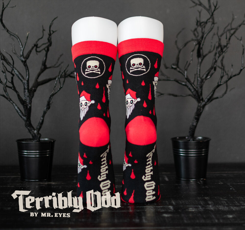 Rear view of Santa Orli Creepmas socks showing the Terribly Odd logo on the soles, red heels, black cuffs, and woven skull and crossbones motifs.